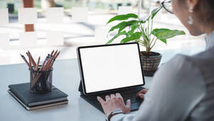 Mockup blank white desktop screen tablet with a woman working in background. White screen tablet for graphic montage.